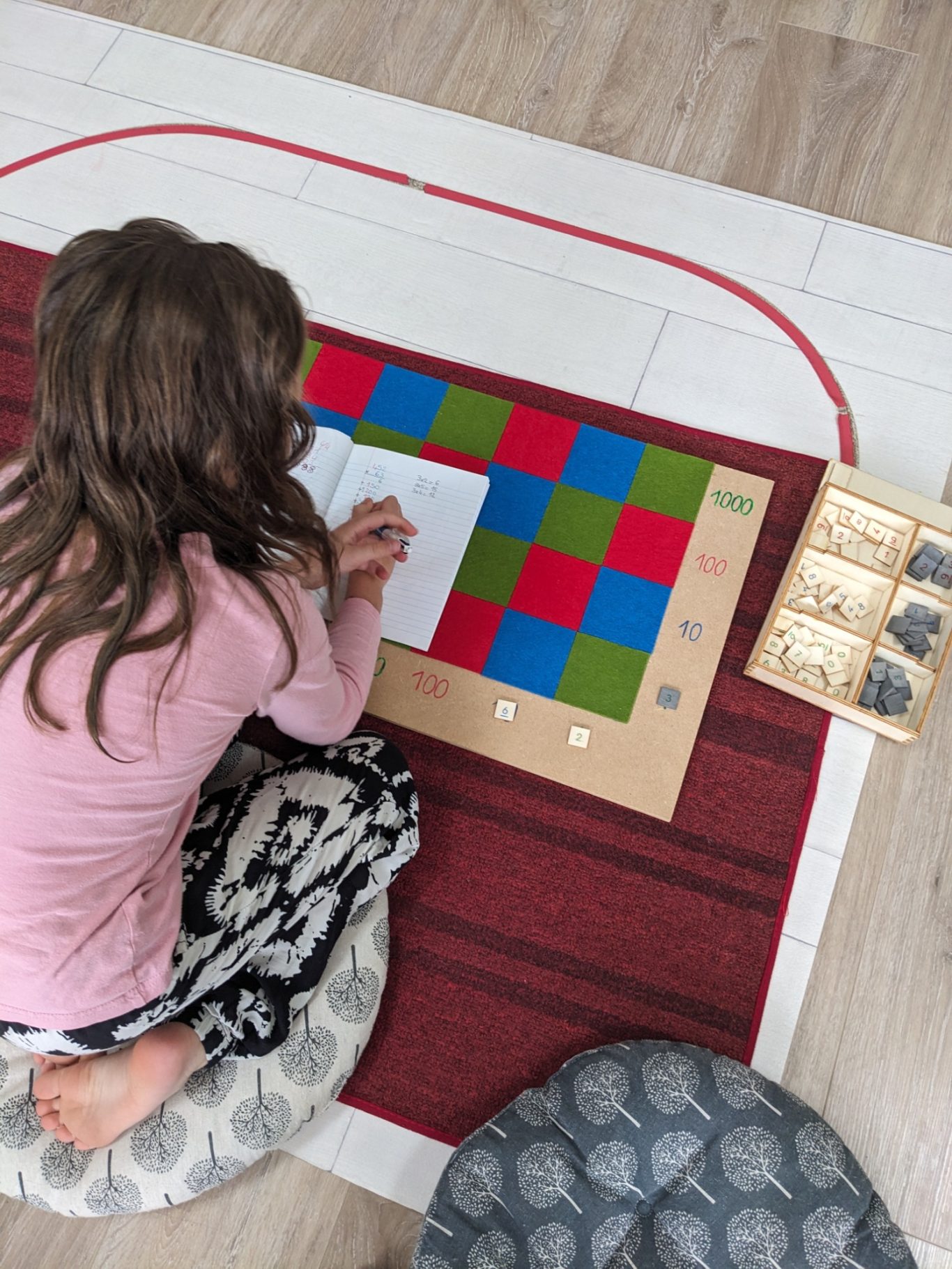 Damier de multiplication Montessori en activité Enfant utilisant le damier de multiplication Montessori